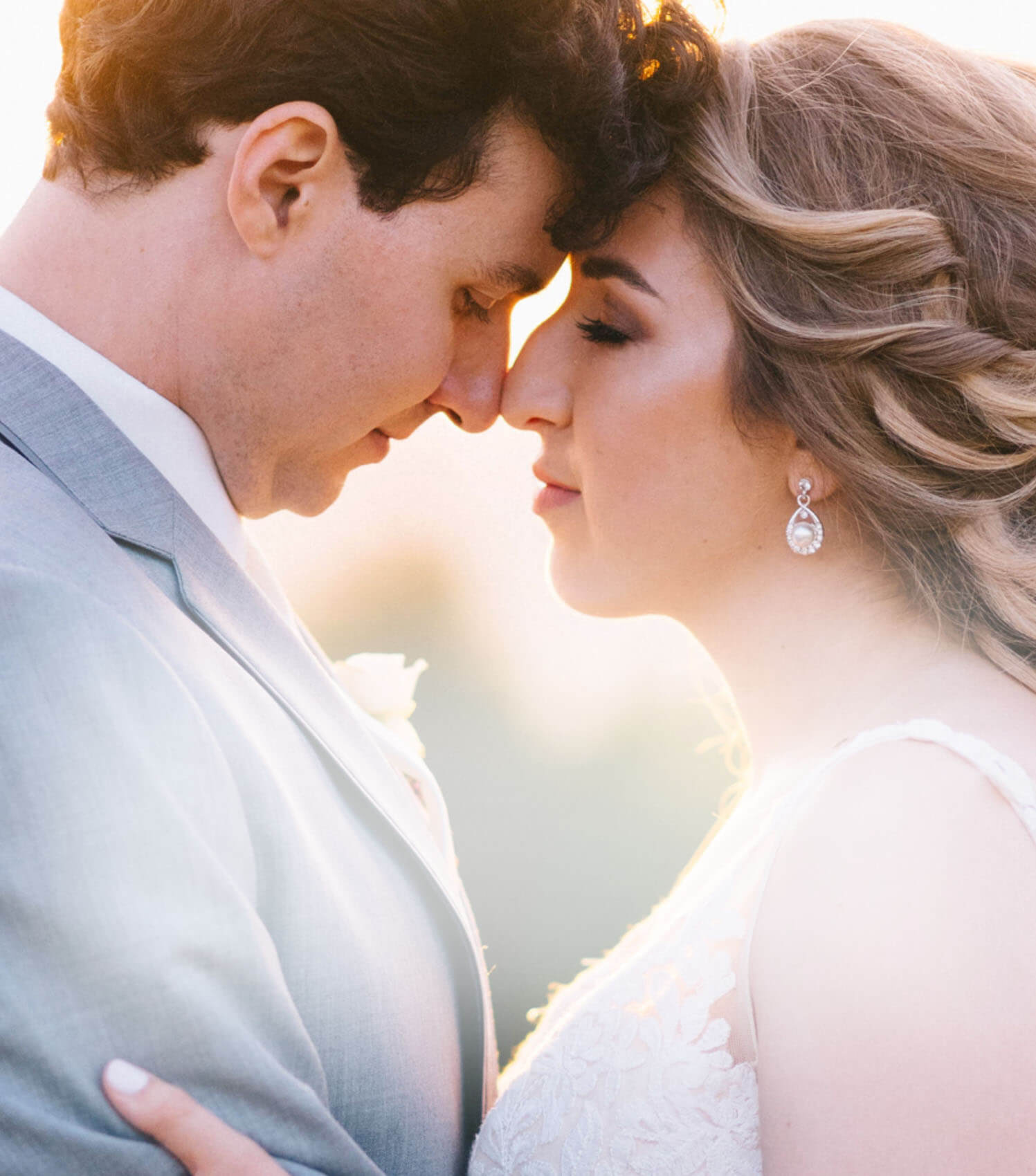 Сouple wearing a white gown and a gray suit. Mobile image